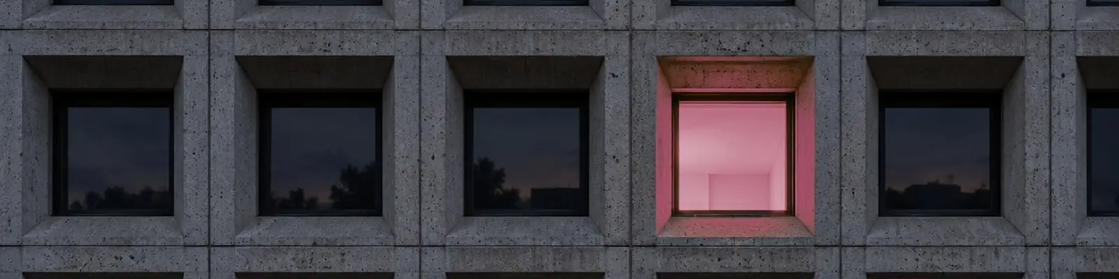 Concrete facade of deep square bays at dusk, one room lit